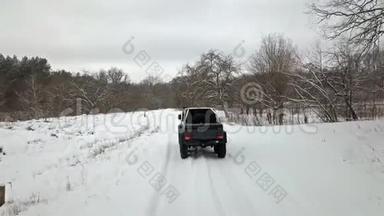 越野车6x6行驶在森林边缘白雪覆盖的乡村道路上，后景